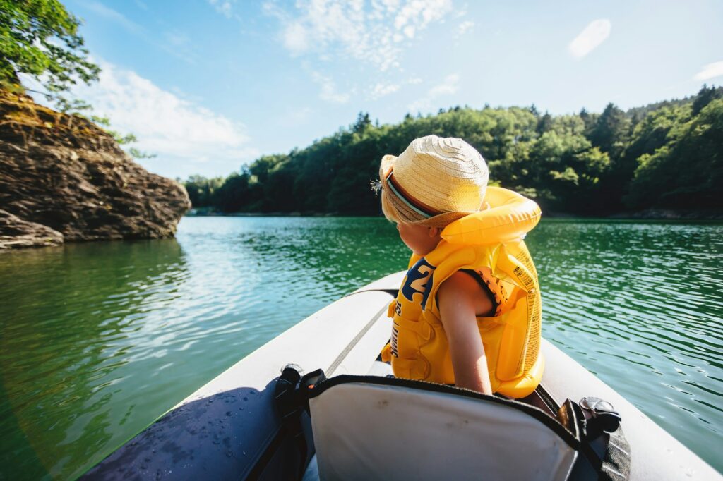 a child in a life jacket on an inflatable kayak floats on the river
