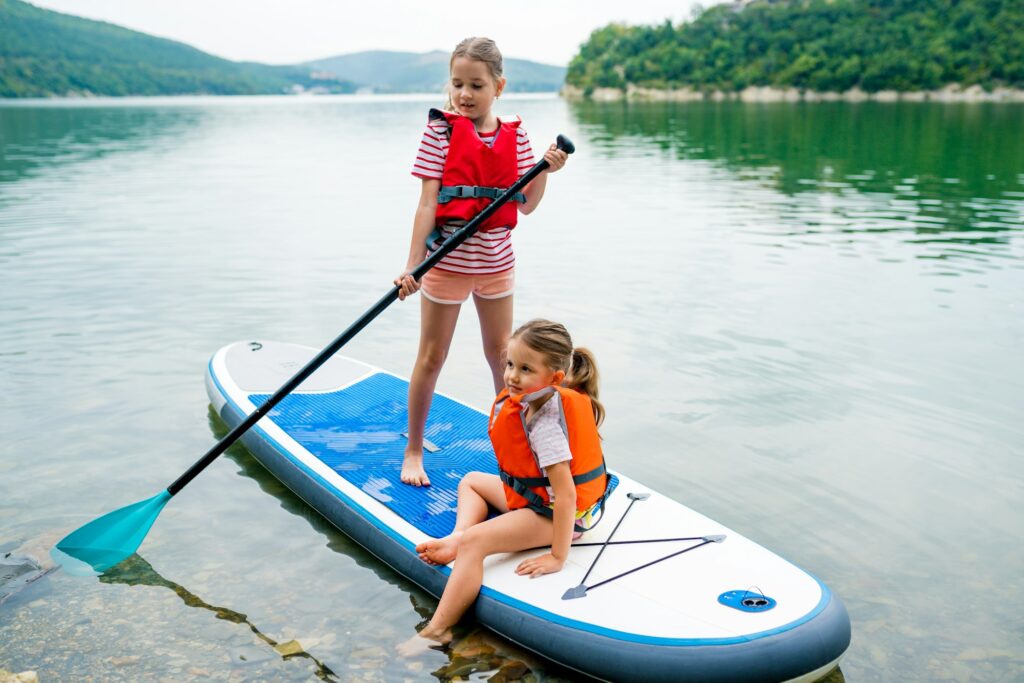 Happy two girls learning stand up paddleboards.