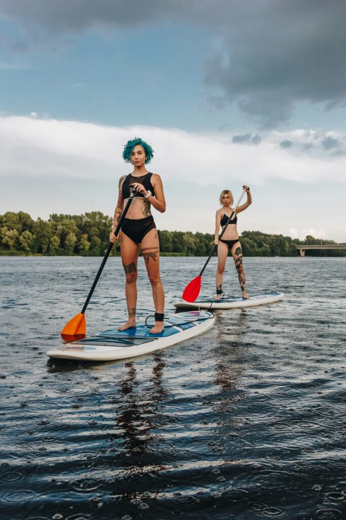 sporty stylish women standup paddleboarding on river